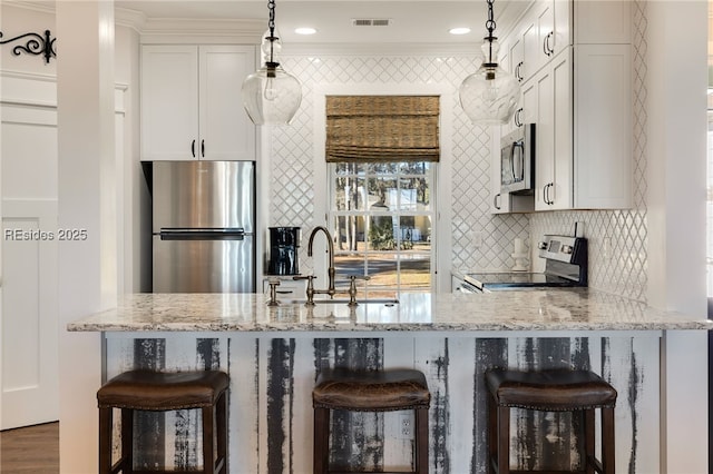 kitchen featuring a breakfast bar, sink, white cabinetry, hanging light fixtures, and stainless steel appliances