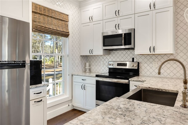 kitchen featuring sink, white cabinetry, appliances with stainless steel finishes, dark hardwood / wood-style flooring, and light stone countertops