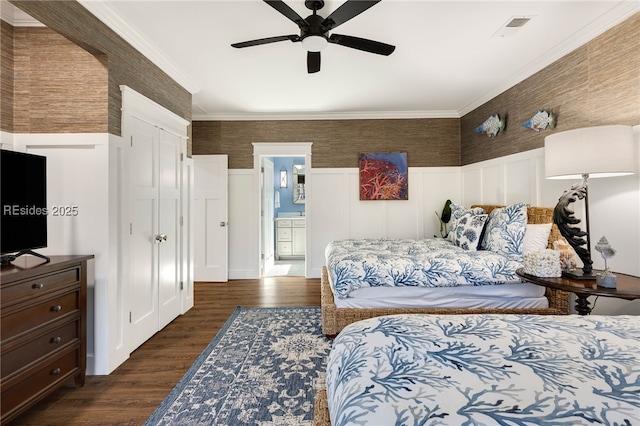 bedroom with ensuite bath, dark wood-type flooring, ornamental molding, and ceiling fan