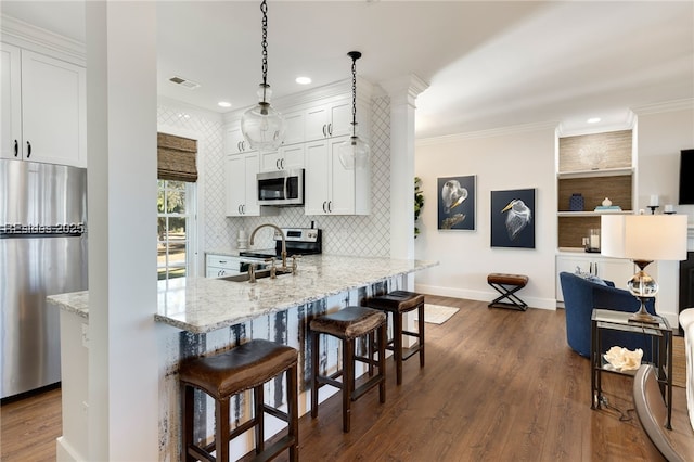 kitchen with white cabinetry, stainless steel appliances, a breakfast bar, and hanging light fixtures