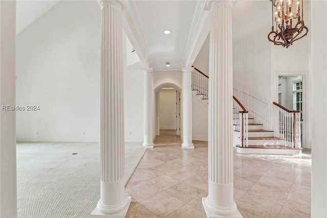 hall with ornamental molding, decorative columns, and a high ceiling