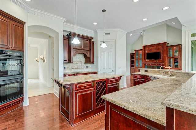 kitchen with sink, black appliances, decorative backsplash, a kitchen island, and decorative light fixtures