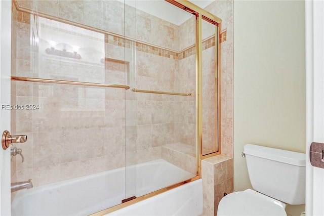 bathroom with toilet and bath / shower combo with glass door