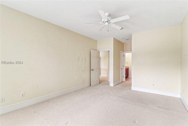 spare room with ceiling fan and light carpet