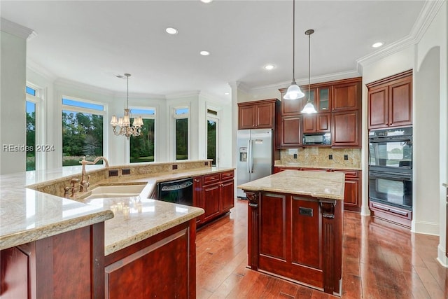 kitchen featuring a large island, sink, crown molding, hanging light fixtures, and black appliances