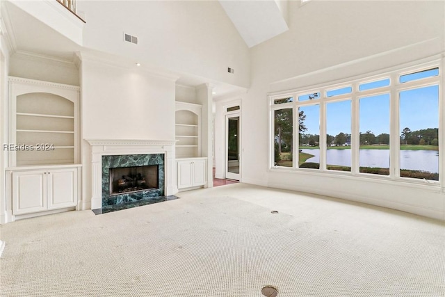 unfurnished living room featuring built in features, carpet, a high ceiling, a water view, and a fireplace