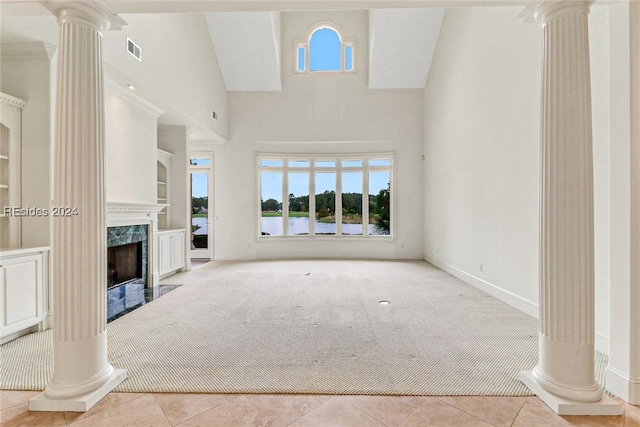 unfurnished living room with built in features, a premium fireplace, a towering ceiling, decorative columns, and light tile patterned flooring