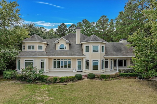 rear view of property with a patio and a lawn