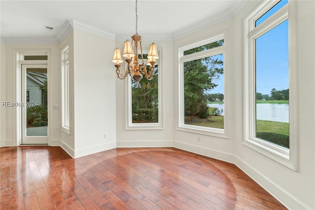 unfurnished dining area with a water view, ornamental molding, an inviting chandelier, and wood-type flooring