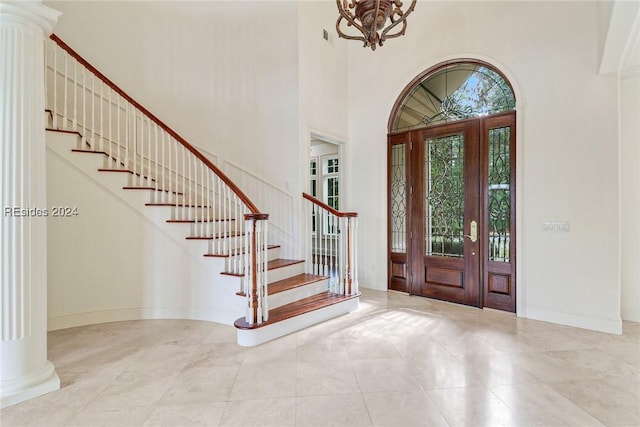 entrance foyer featuring decorative columns, a towering ceiling, and a notable chandelier