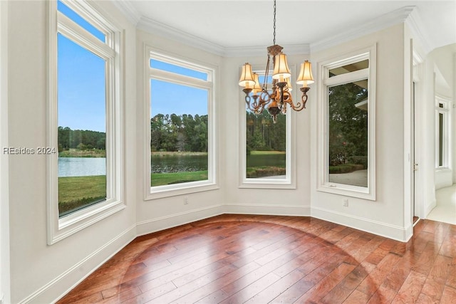 unfurnished dining area with a water view, a notable chandelier, crown molding, and hardwood / wood-style flooring