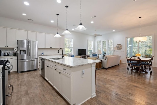 kitchen featuring pendant lighting, appliances with stainless steel finishes, sink, and a center island with sink