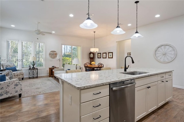 kitchen featuring sink, white cabinetry, decorative light fixtures, stainless steel dishwasher, and a kitchen island with sink