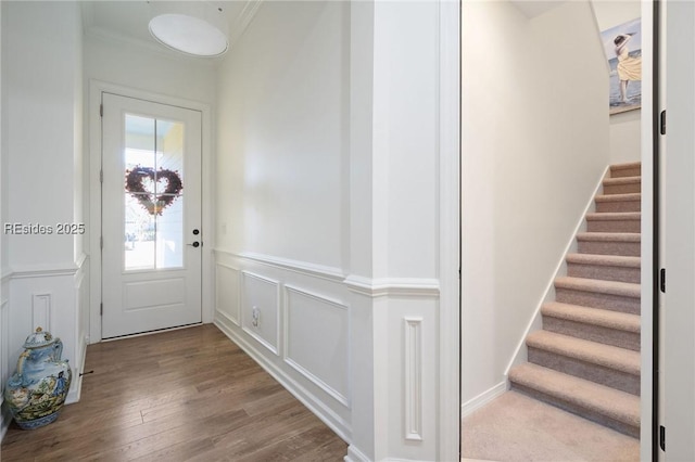 entryway with ornamental molding and hardwood / wood-style floors