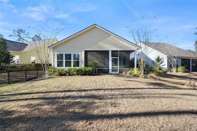 rear view of house featuring a sunroom and a lawn