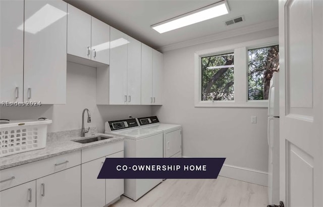 laundry room featuring cabinets, ornamental molding, sink, and washing machine and dryer