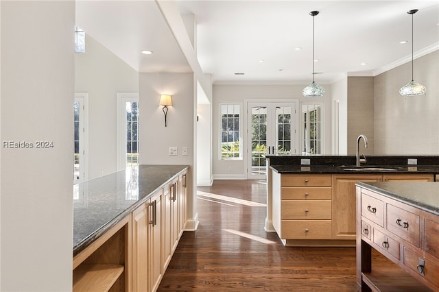 kitchen with pendant lighting, sink, dark stone counters, and light brown cabinets