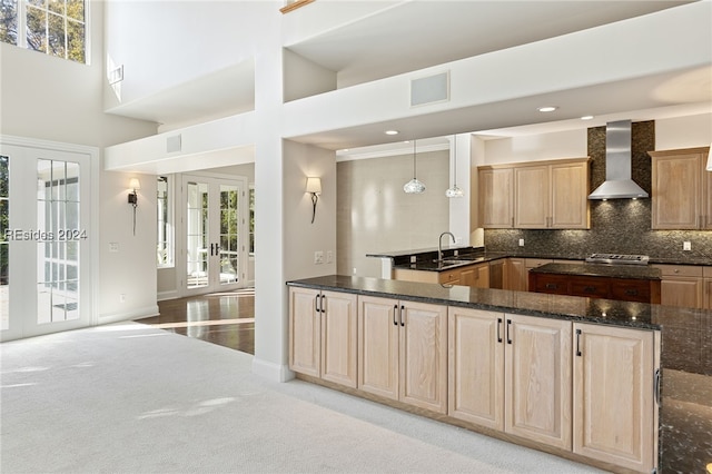 kitchen with french doors, light colored carpet, backsplash, and wall chimney range hood