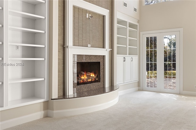 unfurnished living room with built in shelves, plenty of natural light, and carpet flooring