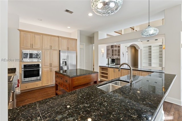 kitchen with appliances with stainless steel finishes, sink, pendant lighting, and light brown cabinetry