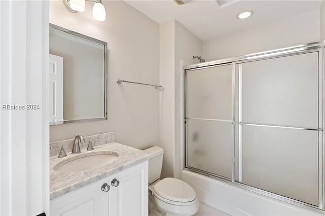 full bathroom with shower / bath combination with glass door, tile patterned floors, vanity, and toilet