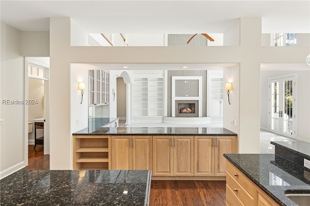 kitchen featuring dark hardwood / wood-style flooring, light brown cabinetry, a high ceiling, and dark stone countertops