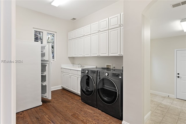 laundry area with cabinets, sink, washer and dryer, and hardwood / wood-style floors