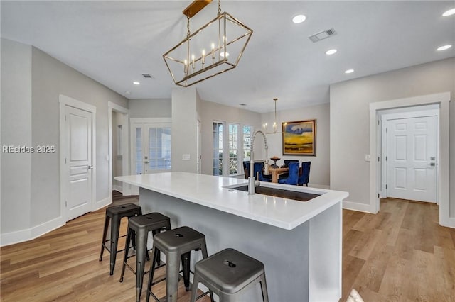 kitchen with sink, an inviting chandelier, a kitchen breakfast bar, a spacious island, and decorative light fixtures