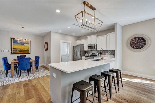 kitchen with stainless steel appliances, a breakfast bar, white cabinets, and decorative light fixtures