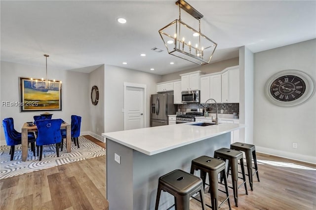 kitchen featuring white cabinetry, sink, decorative light fixtures, and stainless steel appliances