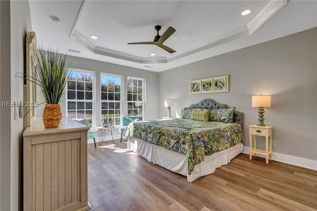 bedroom with ceiling fan, wood-type flooring, a raised ceiling, and ornamental molding