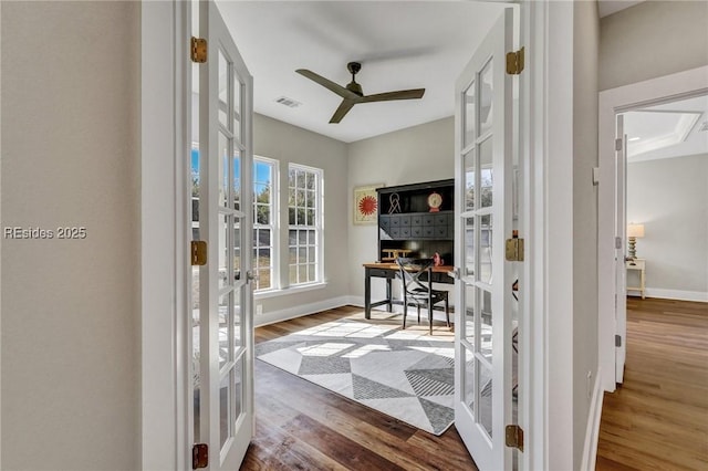 home office featuring wood-type flooring, ceiling fan, and french doors