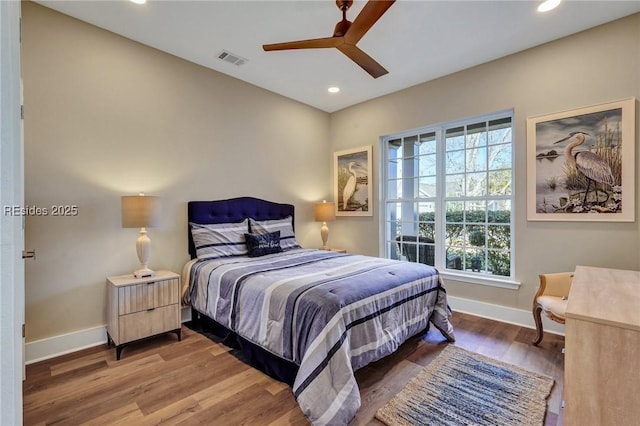 bedroom featuring hardwood / wood-style flooring, ceiling fan, and multiple windows