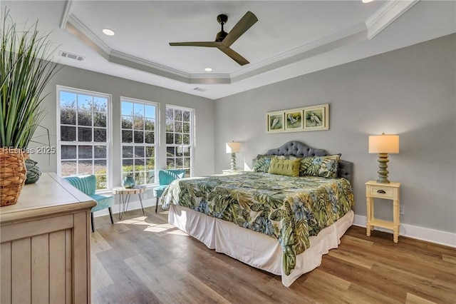 bedroom with crown molding, ceiling fan, a tray ceiling, and hardwood / wood-style floors