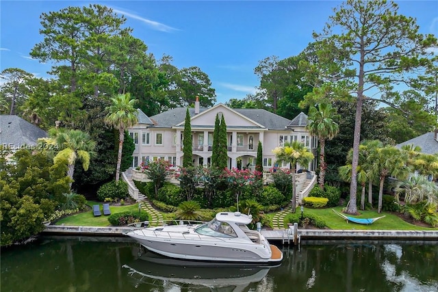 back of house featuring a water view, a balcony, and a yard