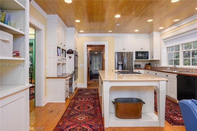 kitchen with white cabinets, a kitchen breakfast bar, a center island, black appliances, and wooden ceiling