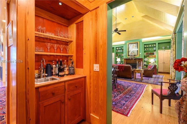 bar featuring sink, light hardwood / wood-style flooring, ceiling fan, and built in shelves