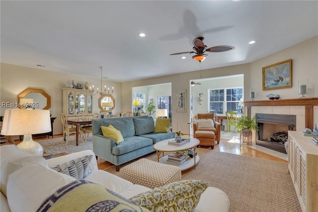 living room featuring ceiling fan with notable chandelier and light wood-type flooring