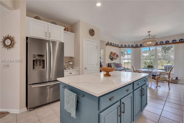 kitchen with pendant lighting, light tile patterned floors, stainless steel fridge, white cabinetry, and a center island