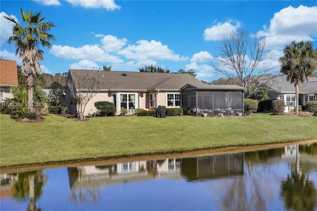 back of property with a water view, a yard, and a sunroom