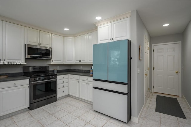 kitchen featuring appliances with stainless steel finishes, light tile patterned floors, and white cabinets