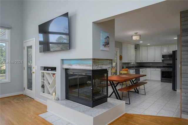 interior space with a multi sided fireplace, sink, and light wood-type flooring