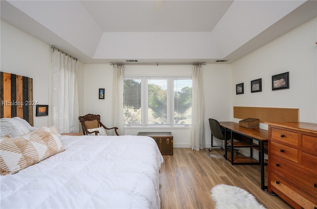 bedroom with a tray ceiling and light hardwood / wood-style floors