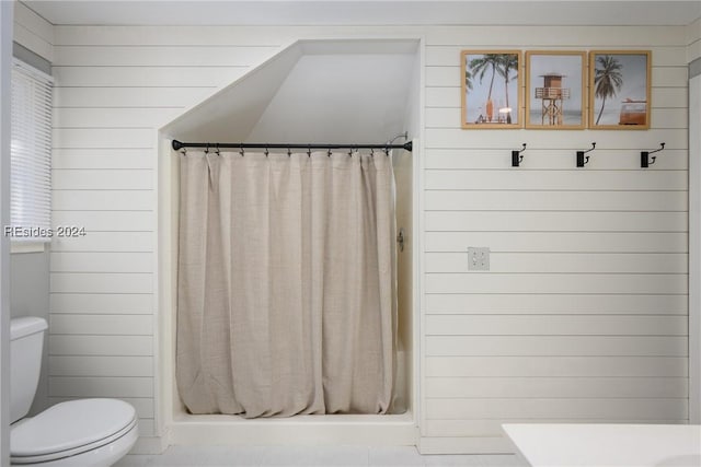 bathroom with wooden walls, toilet, and a shower with shower curtain