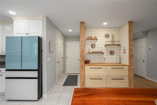 kitchen featuring white cabinetry, butcher block countertops, fridge, and light tile patterned flooring