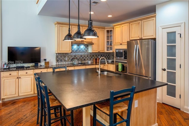 kitchen featuring pendant lighting, sink, stainless steel appliances, a kitchen bar, and light brown cabinetry