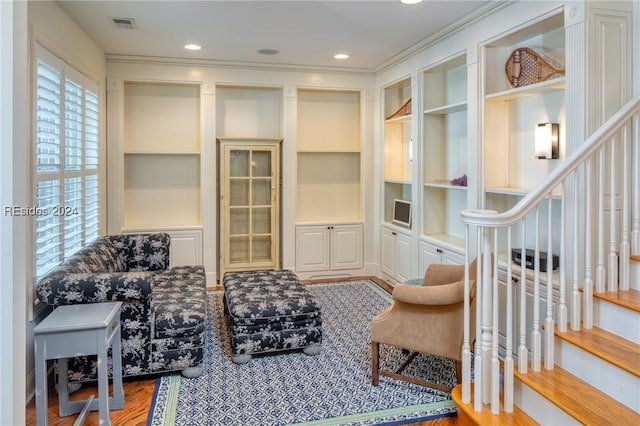 living area featuring hardwood / wood-style flooring, ornamental molding, and built in shelves