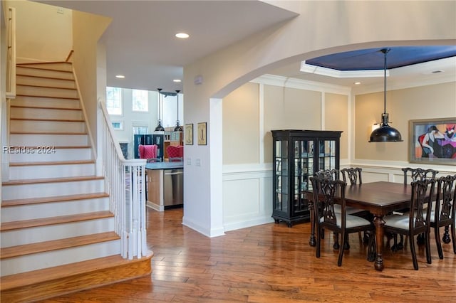 dining space with a raised ceiling, ornamental molding, and hardwood / wood-style floors