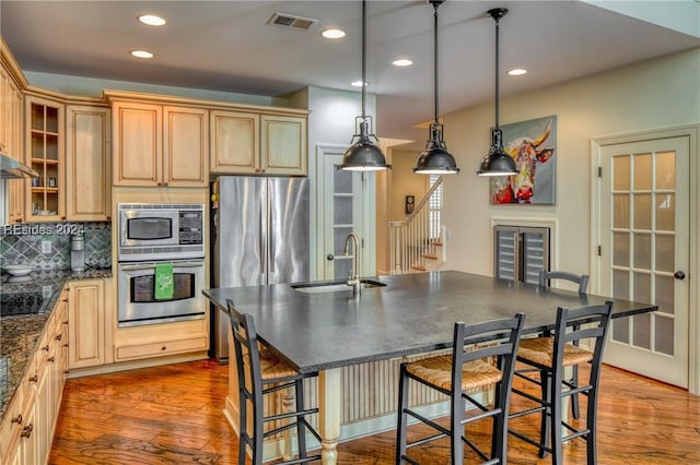 kitchen with pendant lighting, sink, a breakfast bar, stainless steel appliances, and decorative backsplash