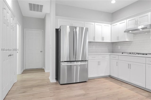 kitchen with tasteful backsplash, white cabinetry, appliances with stainless steel finishes, and light wood-type flooring